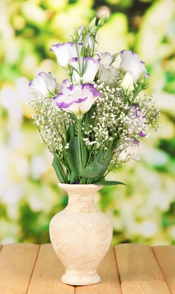 Bouquet of eustoma flowers in vase on wooden table, on bright background — Stock Photo, Image
