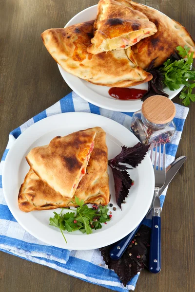 Pizza calzones op platen op servet op houten tafel — Stockfoto