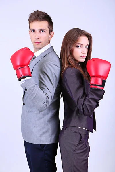 Young business people in boxing gloves on grey background — Stock Photo, Image