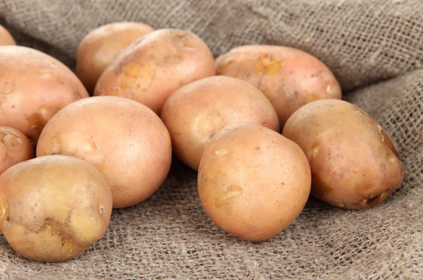 Potato on sackcloth, on wooden table — Stock Photo, Image