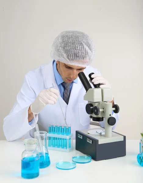 Científico de laboratorio joven mirando el microscopio en el laboratorio — Foto de Stock