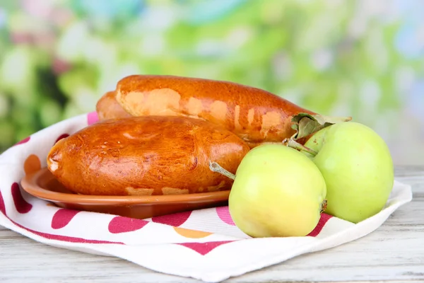 Fresh baked pasties with fruit jam, on wooden table, on bright background — Stock Photo, Image