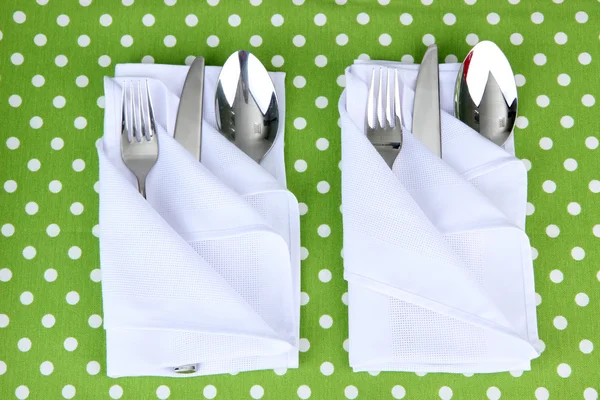 Folded napkin with fork, spoon and knife on color background — Stock Image Folded napkin with fork, spoon and knife on color background Stock Photo