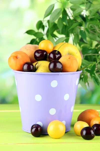 Frutas brillantes de verano en cubo sobre mesa de madera sobre fondo natural —  Fotos de Stock