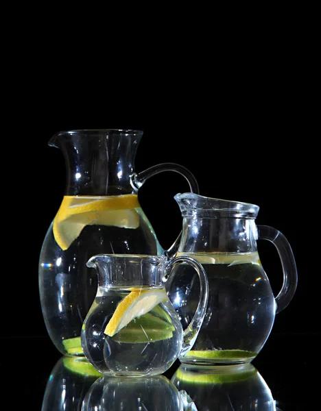 Glass pitchers of water isolated on black — Stock Photo, Image