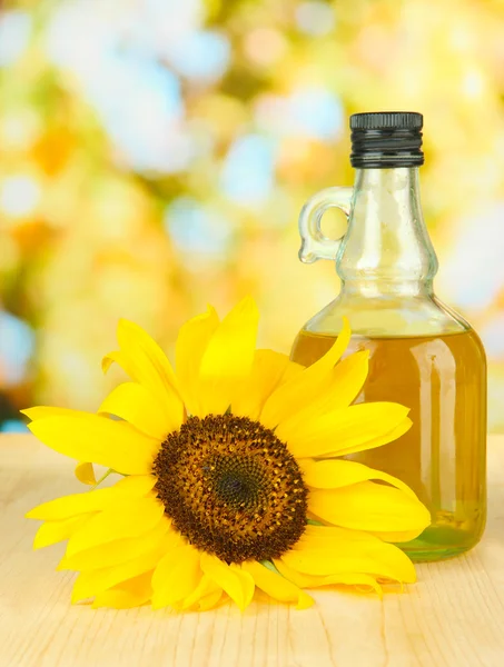Öl im Glas und Sonnenblumen auf Holztisch in Großaufnahme — Stockfoto