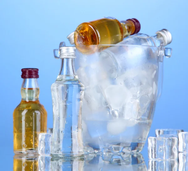 Minibar-Flaschen im Eimer mit Eiswürfeln, auf farbigem Hintergrund — Stockfoto