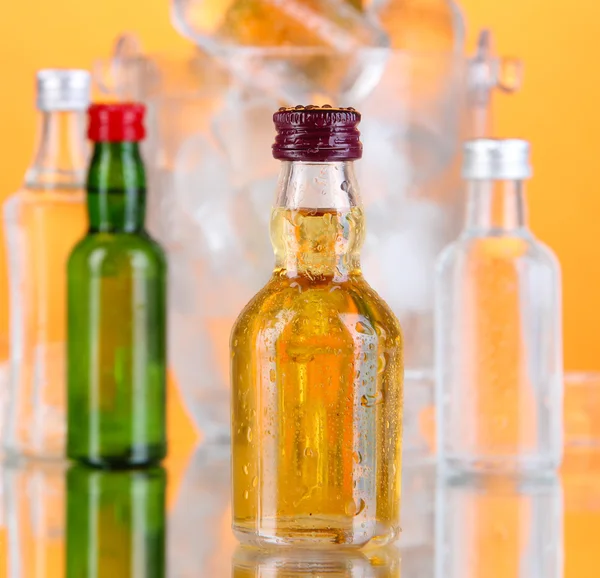 Мінібар пляшки в відрі з кубиками льоду, на кольоровому фоні — стокове фото