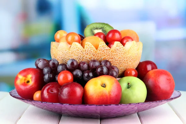 Assortment of juicy fruits on wooden table, on bright background — Stock Photo, Image