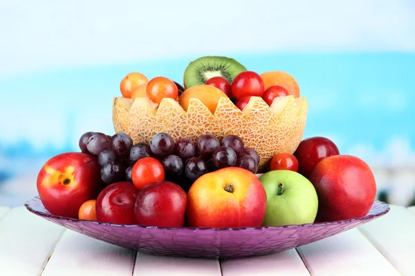 Assortment of juicy fruits on wooden table, on bright background — Stock Photo, Image