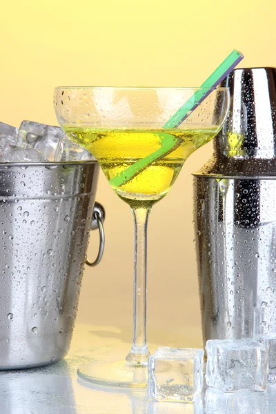 Metal ice bucket and shaker and cocktail on yellow background — Stock Photo, Image