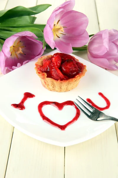 Süße Torte mit Erdbeere und Soße auf Teller, auf Holzgrund — Stockfoto
