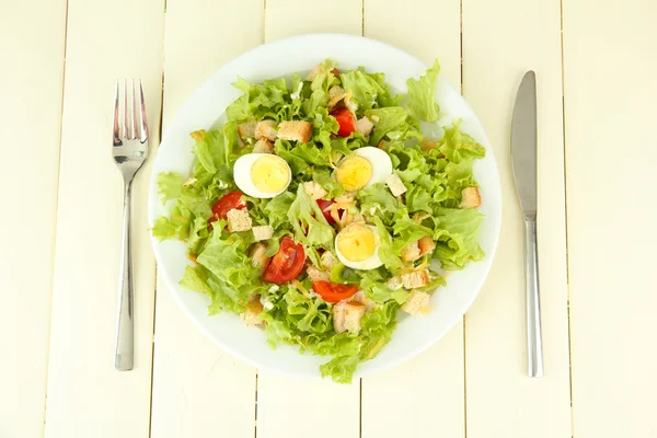 Ensalada César sobre plato blanco, sobre fondo de madera color —  Fotos de Stock