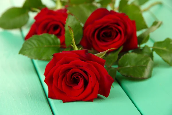 Hermosas rosas, sobre fondo de madera de color — Foto de Stock