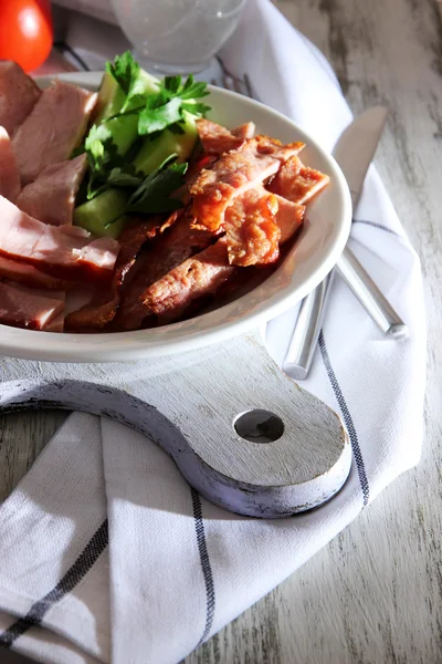 Tocino en plato a bordo en servilleta a bordo en mesa de ventana — Foto de Stock