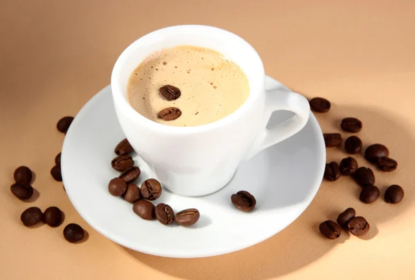 Tazza di caffè con chicchi di caffè su sfondo beige — Foto Stock