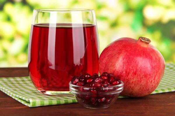 Glass of fresh garnet juice on table on bright background — Stock Photo, Image