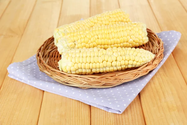 Свежая кукуруза на плетеном коврике, на деревянном фоне — стоковое фото