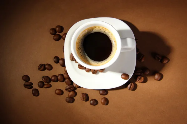 Taza de café con granos de café sobre fondo marrón —  Fotos de Stock