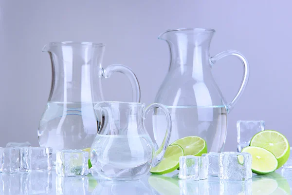 Glas kannor vatten med is och lime på grå bakgrund — Stockfoto