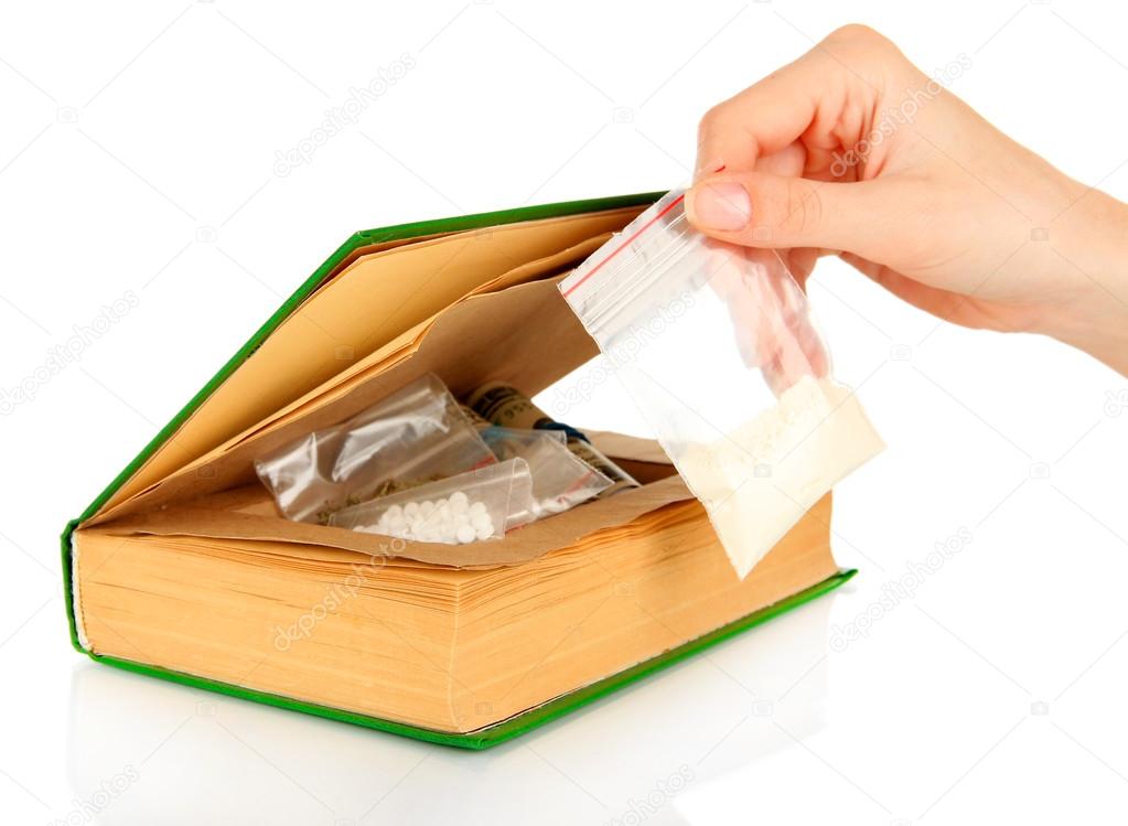 Hand holding narcotics near book-hiding place isolated on white