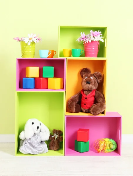 Estantes brillantes de diferentes colores con juguetes sobre fondo de pared —  Fotos de Stock