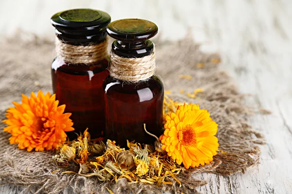 Geneeskundeflessen en calendula bloemen op houten achtergrond — Stockfoto