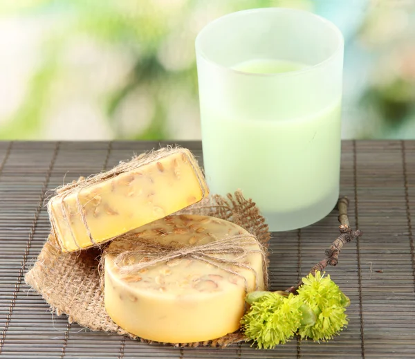 Hand made soap on grey bamboo mat, on green background — Stock Photo, Image