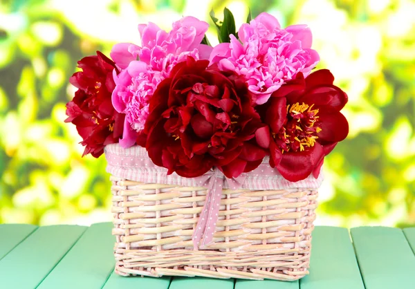 Belles pivoines dans le panier en osier sur la table sur fond lumineux — Photo