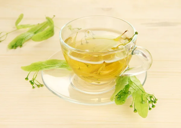 Glass cup of tea with linden on wooden table close-up — Stock Photo, Image