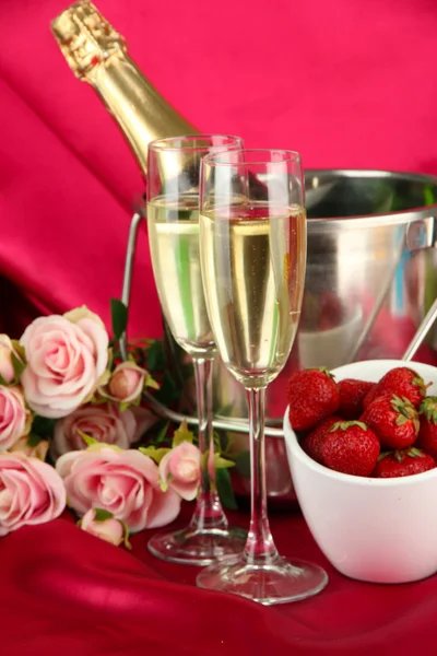 Bodegón romántico con champán, fresa y rosas rosadas, sobre fondo de tela de color — Foto de Stock