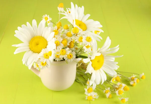 Beautiful bouquet chamomiles in pitcher on wooden table close-up — Stock Photo, Image