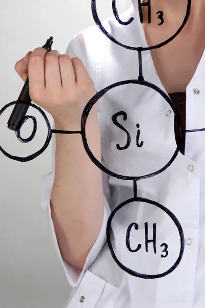 Chemist woman writing formulas on glass on grey background — Stock Photo, Image