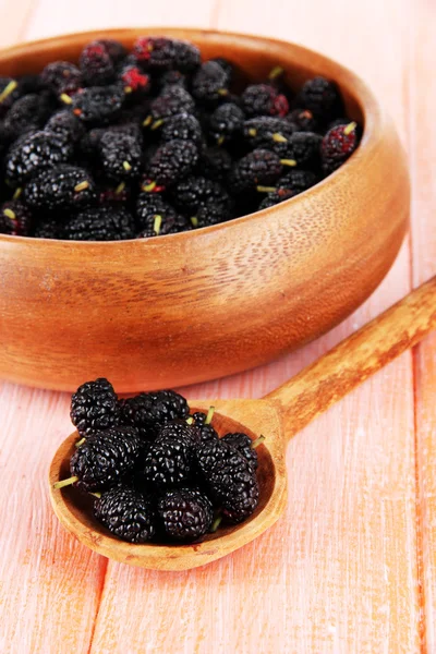 Moras maduras en tazón y cuchara sobre fondo de madera — Foto de Stock