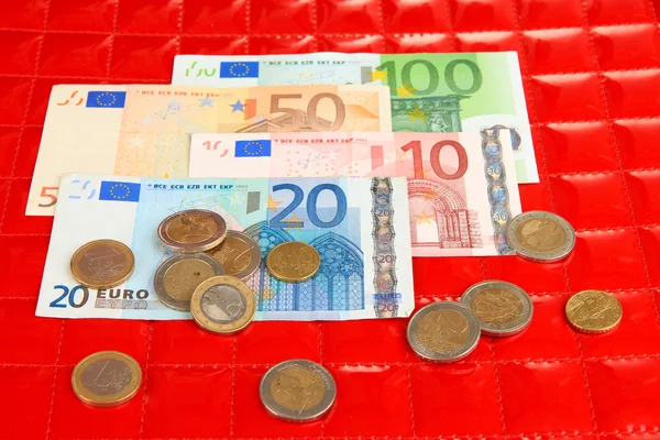 Euro-sedlar och eurocent på röd bakgrund — Stockfoto