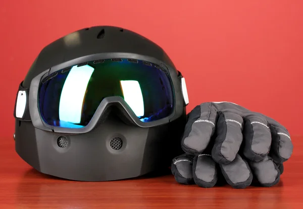 Winter sport glasses, helmet and gloves, on red background — Stock Photo, Image