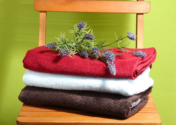 Handtücher und Blumen auf Holzstuhl auf grünem Hintergrund — Stockfoto