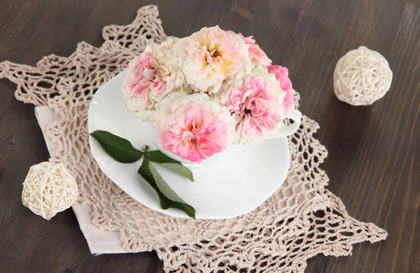 Rosen in Tasse auf Servietten auf Holzgrund — Stockfoto