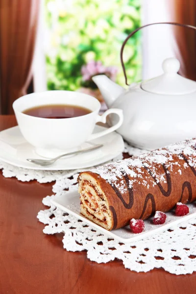 Sweet roll with cup of tea on table in room — Stock Photo, Image