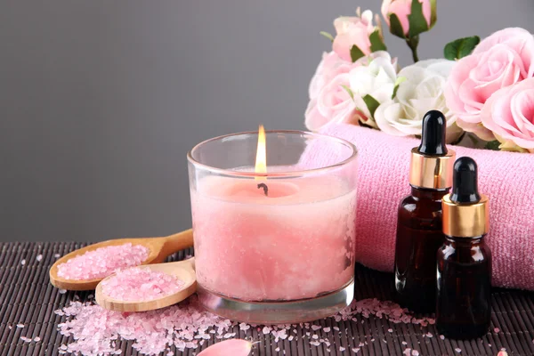 Красивая розовая свеча с цветами и полотенцем на бамбуковом коврике — стоковое фото