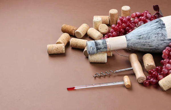 Eski şişe şarap, üzüm ve mantarlar kahverengi zemin üzerinde — Stok fotoğraf