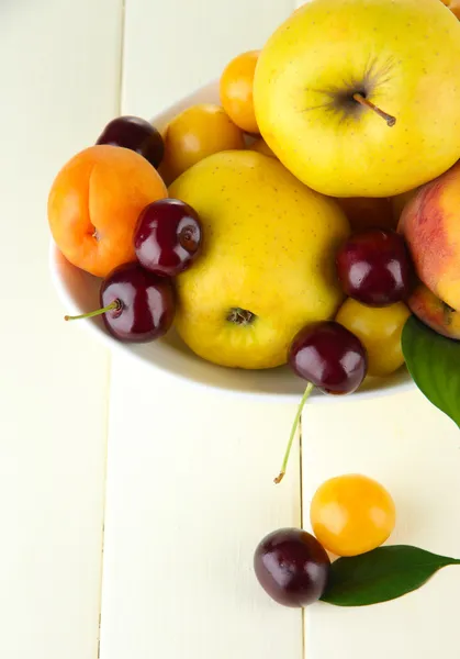 Frutas de verano brillantes en plato en la mesa de madera de cerca —  Fotos de Stock