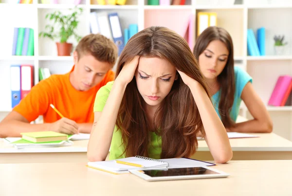 Grupo de jóvenes estudiantes sentados en la biblioteca — Foto de Stock