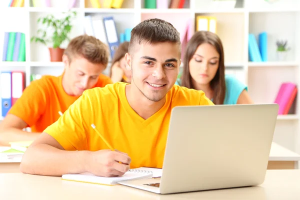 Grupo de jóvenes estudiantes sentados en la biblioteca — Foto de Stock