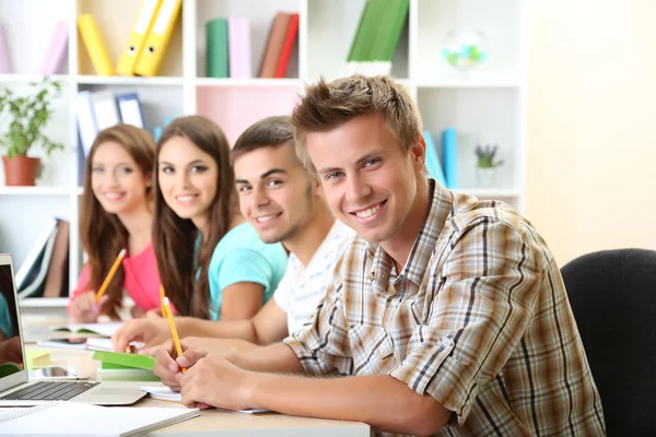 Grupo de jóvenes estudiantes sentados en la biblioteca — Foto de Stock