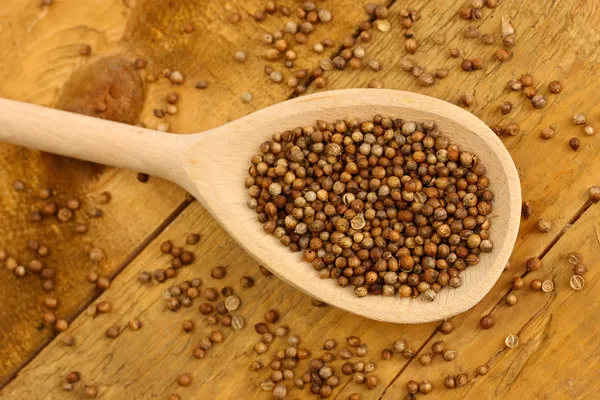 Montón de semillas de cilantro en cuchara de madera sobre fondo de madera de cerca — Foto de Stock