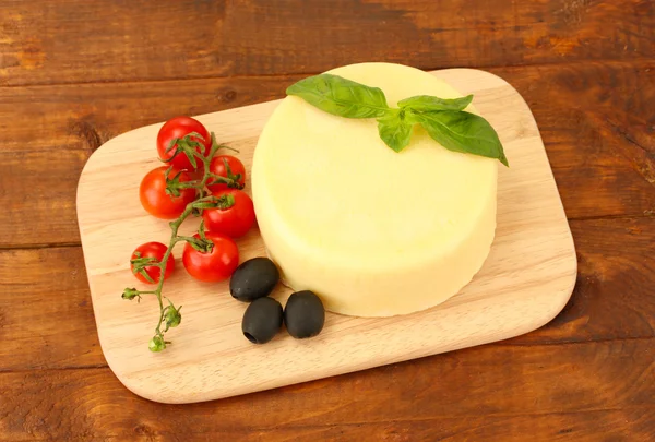 Cheese mozzarella with vegetables on the cutting board on wooden background — Stock Photo, Image