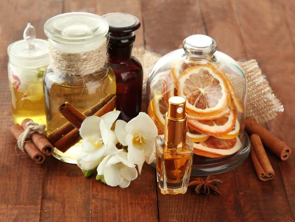Garrafas com ingredientes para o perfume em fundo de madeira — Fotografia de Stock