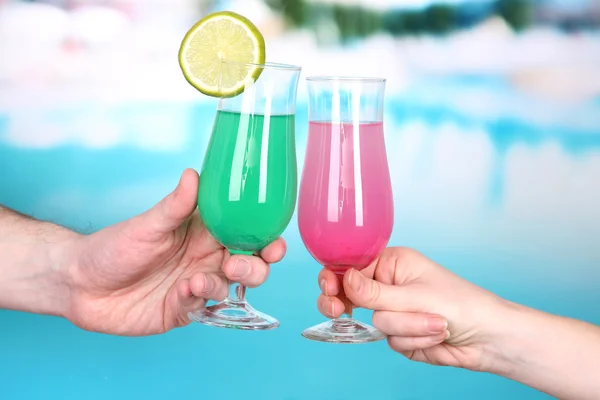 Cocktails dans les mains des hommes et des femmes sur fond de piscine — Photo