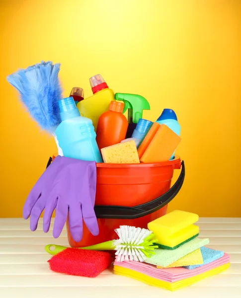 Reinigungsartikel im Eimer auf farbigem Hintergrund — Stockfoto